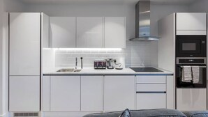 Una cocina moderna con armarios blancos, una campana extractora de acero inoxidable y un horno empotrado.
