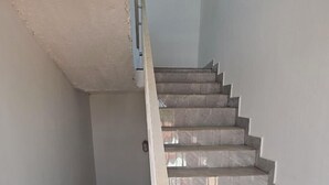 A staircase with a handrail, leading to a door with a light switch. - Kaira kunda (Sanyang)