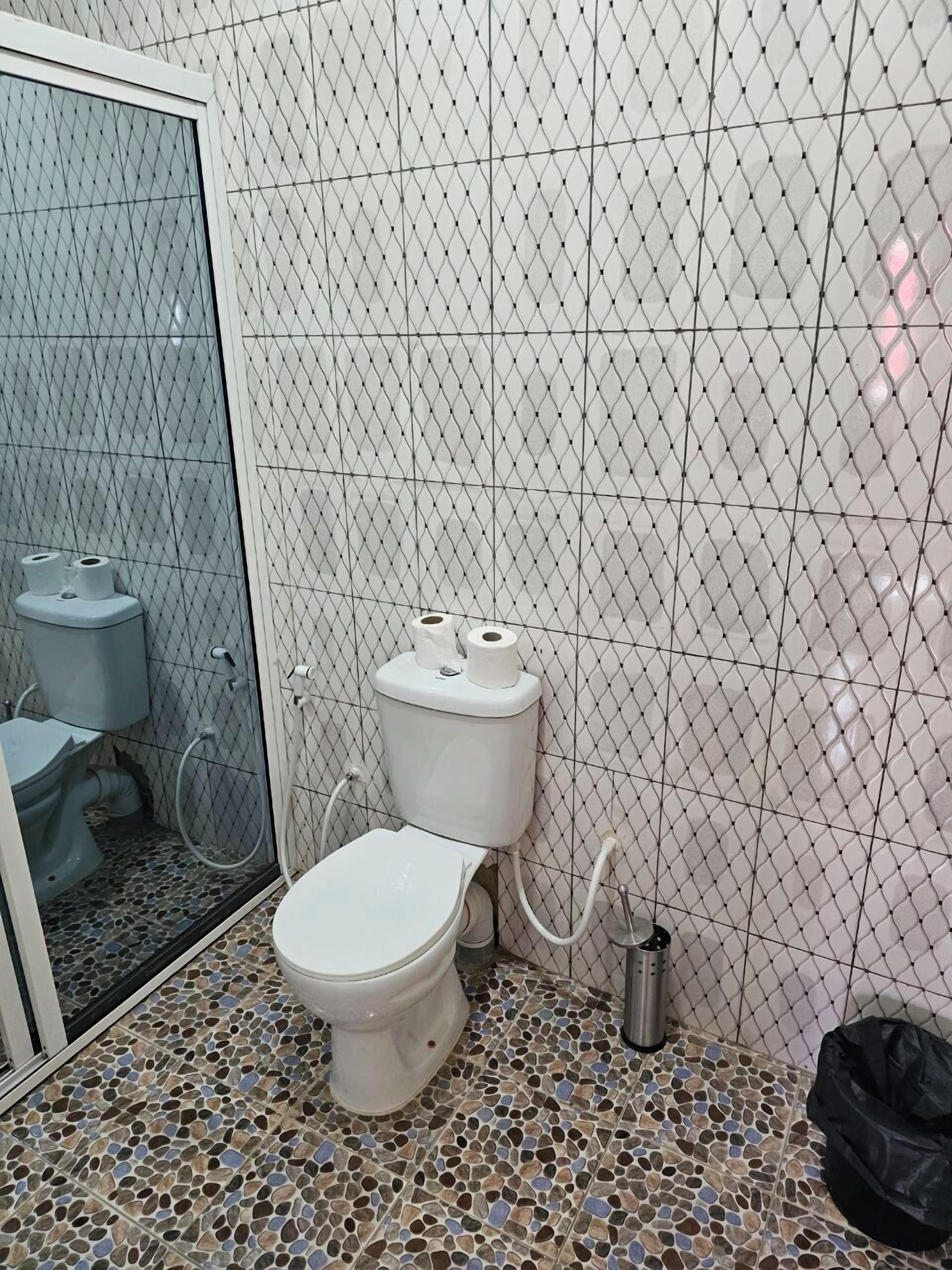 Casa de banho com sanita branca, bidé e zona de duche.