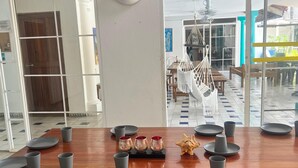 A modern dining area with a wooden table set for six, surrounded by glass walls. - Coral house San Andres (San Andrés)