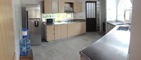 A kitchen with a refrigerator, microwave, stove, and sink.