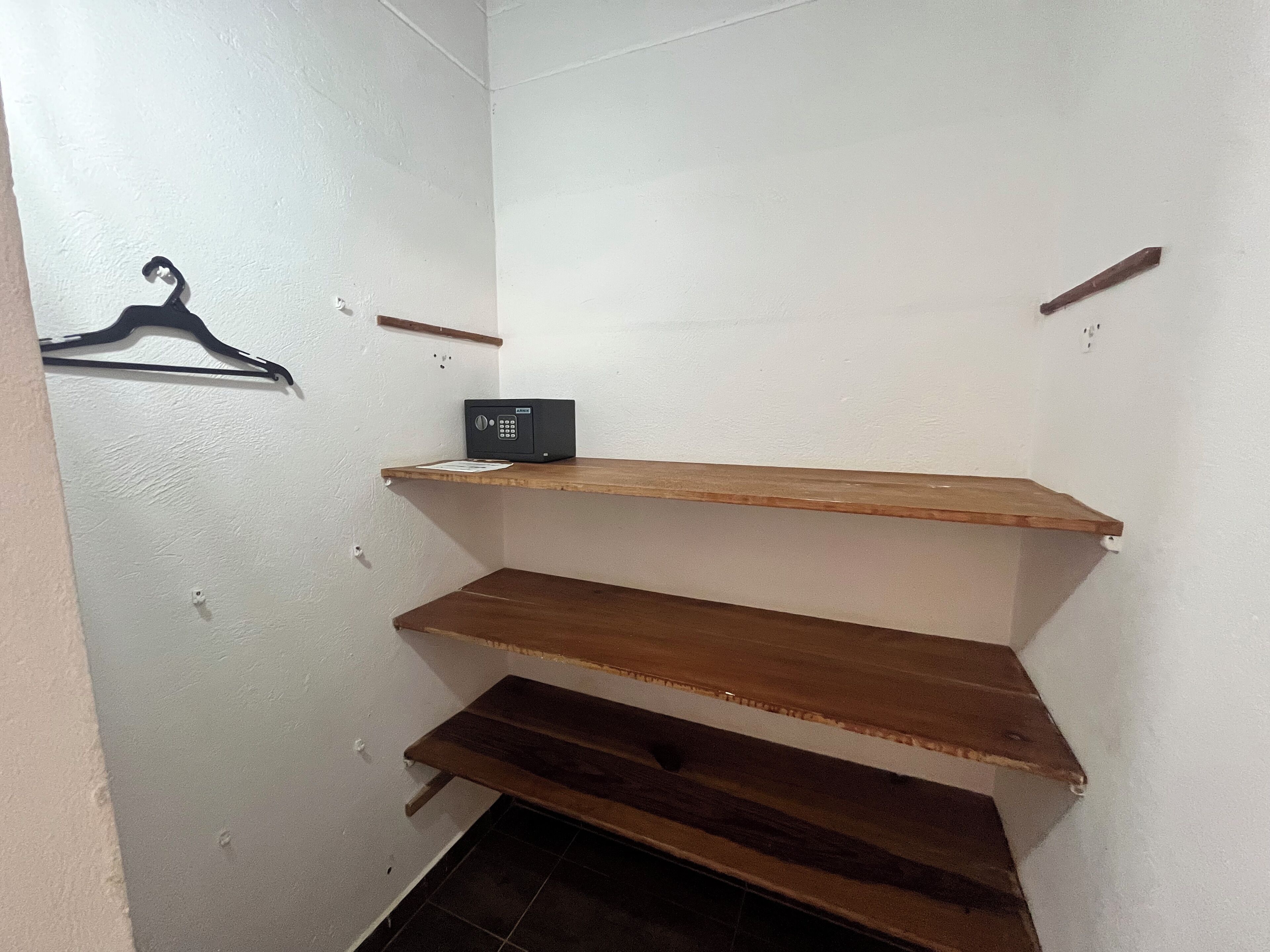 Un espacio de almacenamiento pequeño y cerrado con estanterías de madera y una caja fuerte negra.