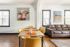 Un comedor con mesa de madera, sillas amarillas y individuales naranja.