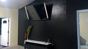 A room with a black accent wall, a white console table with drawers, a mirror, and a plant. - D’Emerald of the Sea - Unit 5, Mid-Island 2-Bed Modern Apartment near the Beach (Christiansted)