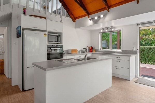 A modern kitchen with a central island, built-in appliances, and large windows.