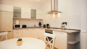 A modern kitchen with white cabinets, a stainless steel range hood, a microwave, and a coffee maker. - Beautiful, cozy, family-friendly apartment in the middle of nature. (Sigulda)