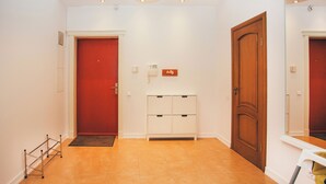 A hallway with a red door, a white cabinet, and a wooden door. - Beautiful, cozy, family-friendly apartment in the middle of nature. (Sigulda)
