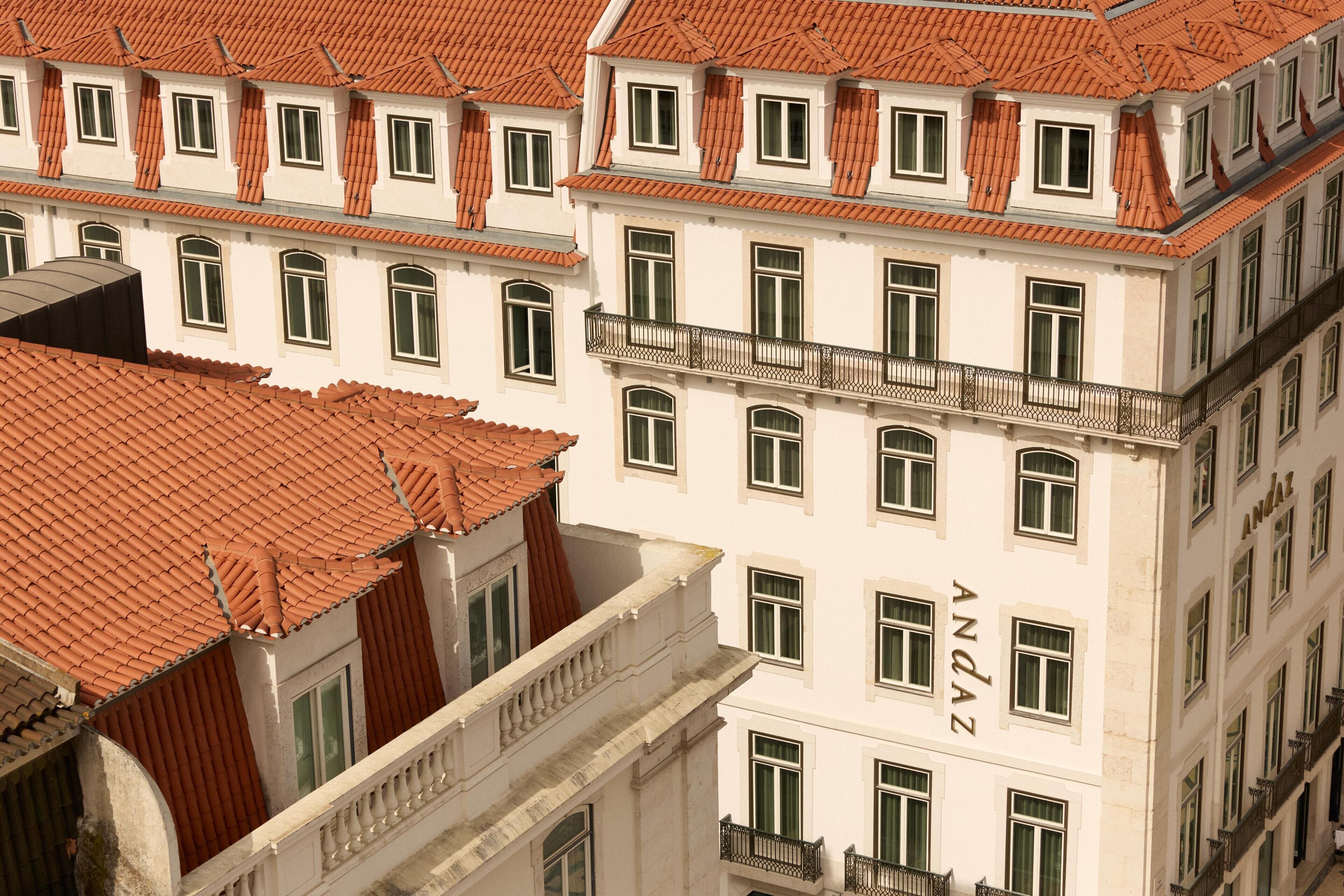 A multi-story building with a red-tiled roof and white walls, featuring multiple windows and balconies.