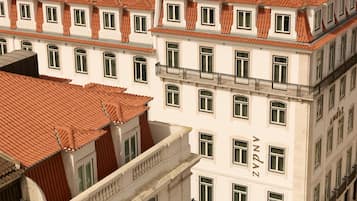 Un edificio de varios pisos con tejado de tejas rojas y paredes blancas, con múltiples ventanas y balcones.