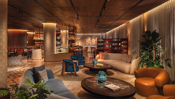 Un vestíbulo de hotel moderno con un bar, zona de estar y una planta grande.