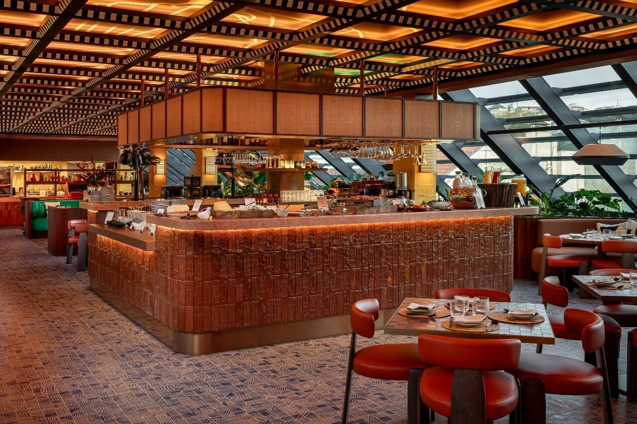 A restaurant with a central bar area, seating arrangements, and a patterned ceiling.