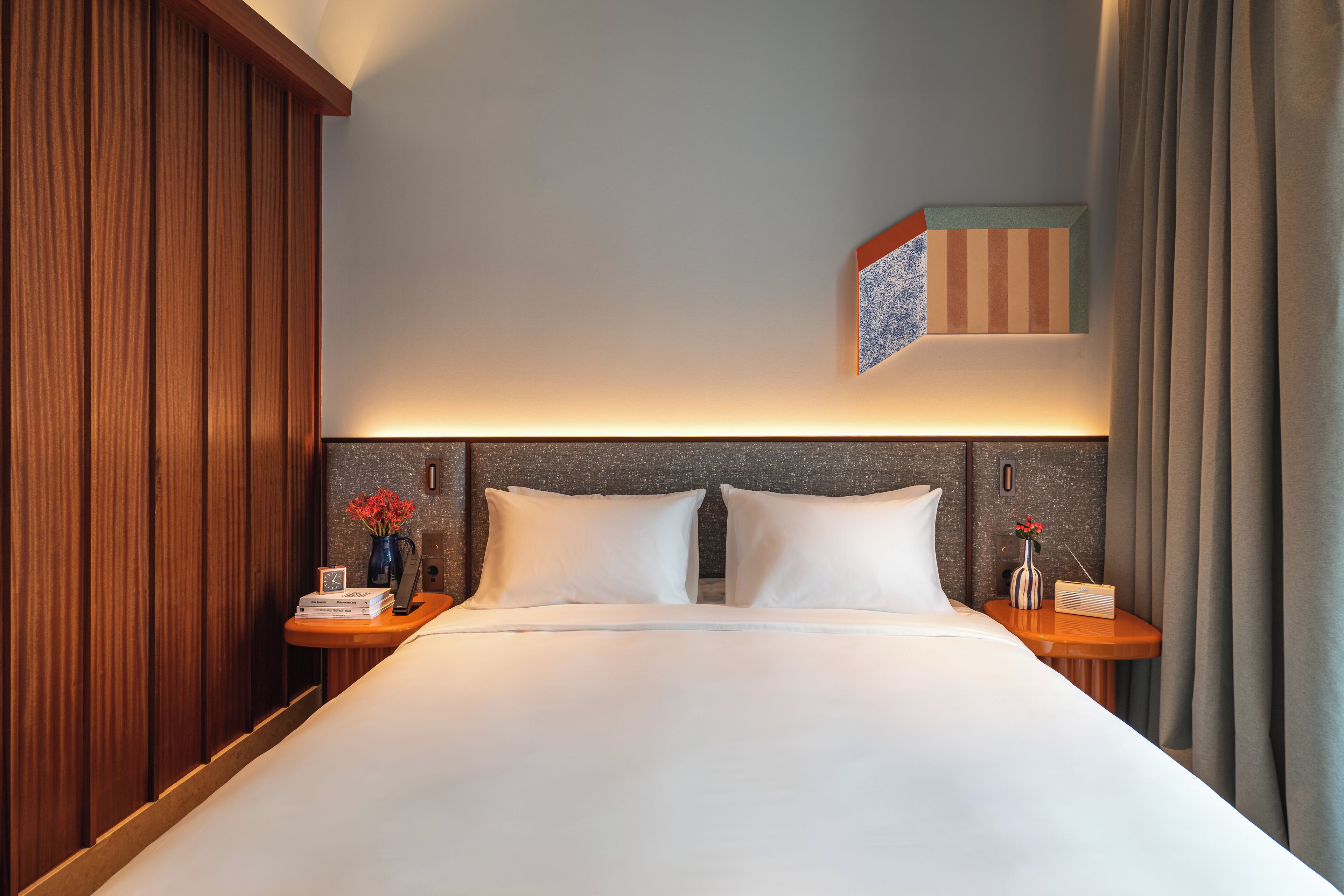 A neatly made bed with white linens, two bedside tables with lamps, and a small decorative item on one table.
