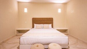 Une chambre spacieuse avec un grand lit, deux tables de chevet et une tête de lit.