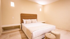 Une chambre à coucher avec un grand lit, une tête de lit, deux tables de chevet et deux poufs.