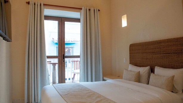 A hotel room with a large bed, a wooden headboard, and a balcony with a view.