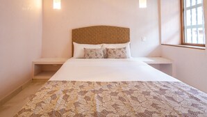 A neatly arranged bedroom with a large bed, two bedside tables, and a window with curtains.