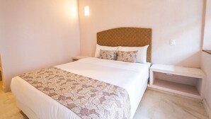 A neatly arranged bedroom with a large bed, a headboard, and bedside tables.