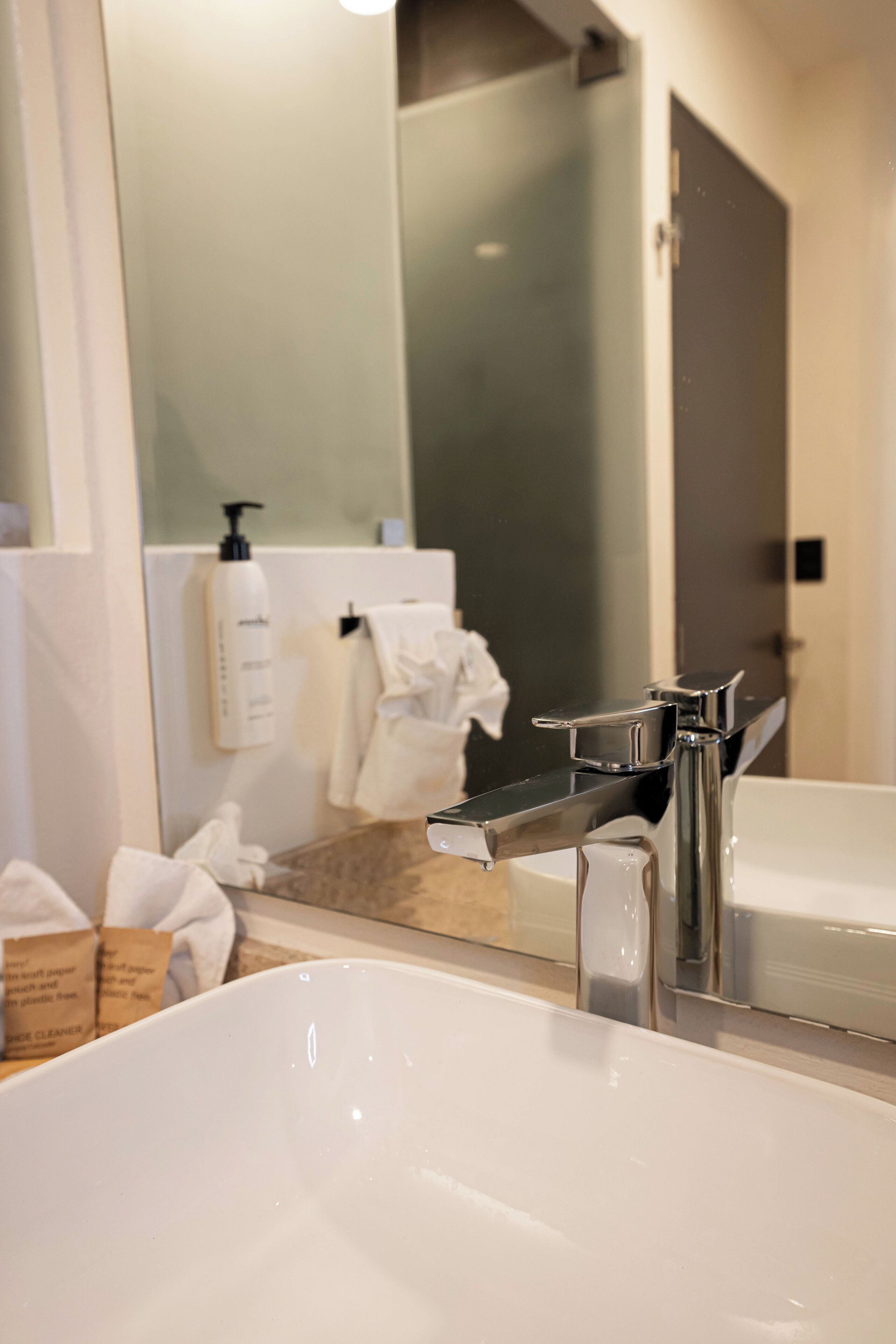 Un baño con un espejo grande, un lavamanos blanco y una zona de ducha.