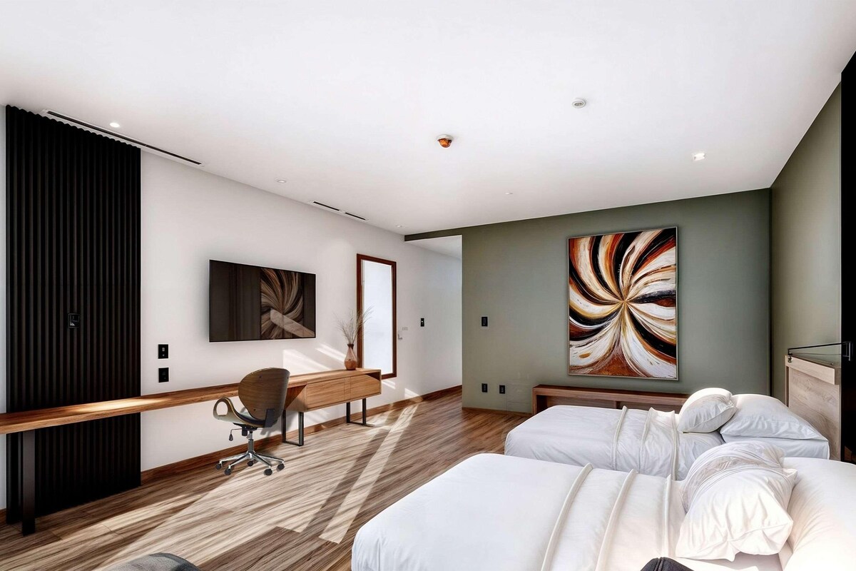 A modern hotel room with a large bed, a desk, and a chair.