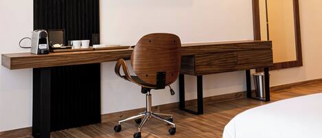 Habitación de hotel moderna con un escritorio de madera, una silla, una cama, un televisor de pantalla plana y un espejo grande.