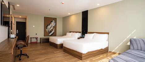 A hotel room with two beds, a desk, a chair, and a TV.