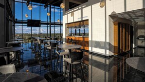 A modern bar area with high ceilings, large windows, and a bar counter. - Radisson San Luis Potosi Aeropuerto (San Luis Potosi)