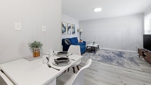 A modern living room with a dining area, a blue sofa, a TV, and a lamp.