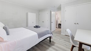 A bedroom with a bed, bedside tables, a desk, and a wardrobe.