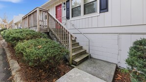 A residential building with a red door, white siding, and a front porch.