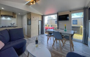 A modern living room with a sofa, a dining table with chairs, and a kitchen area with a refrigerator and stove. - Amazing home in Lauwersoog with WiFi (Lauwersoog)