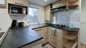 Een moderne keuken met een zwart aanrecht, houten kastjes, een ingebouwde magnetron, een gasfornuis en een raam met uitzicht op de omgeving.