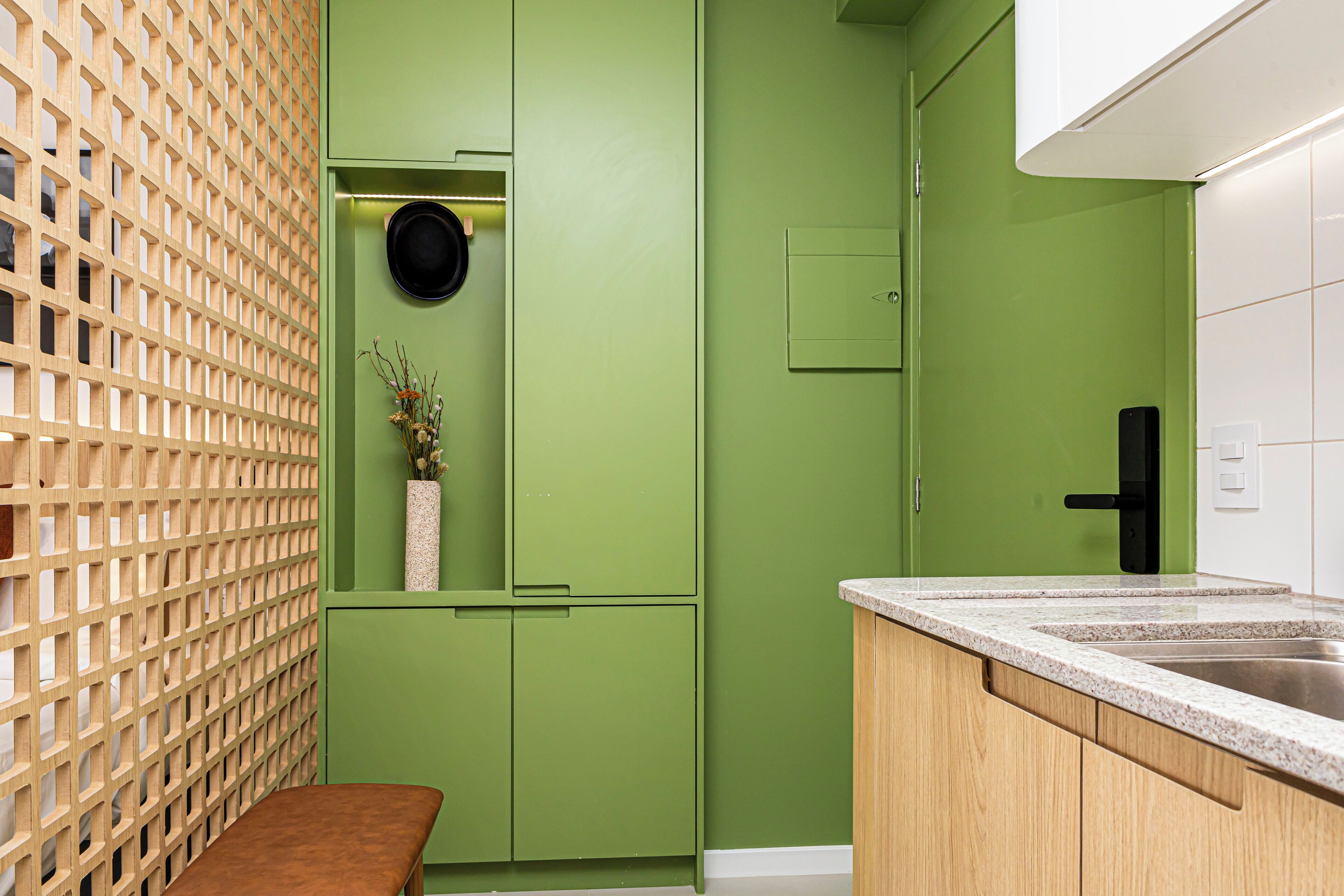 Una cocina con gabinetes verdes, un banco de madera y un lavamanos.