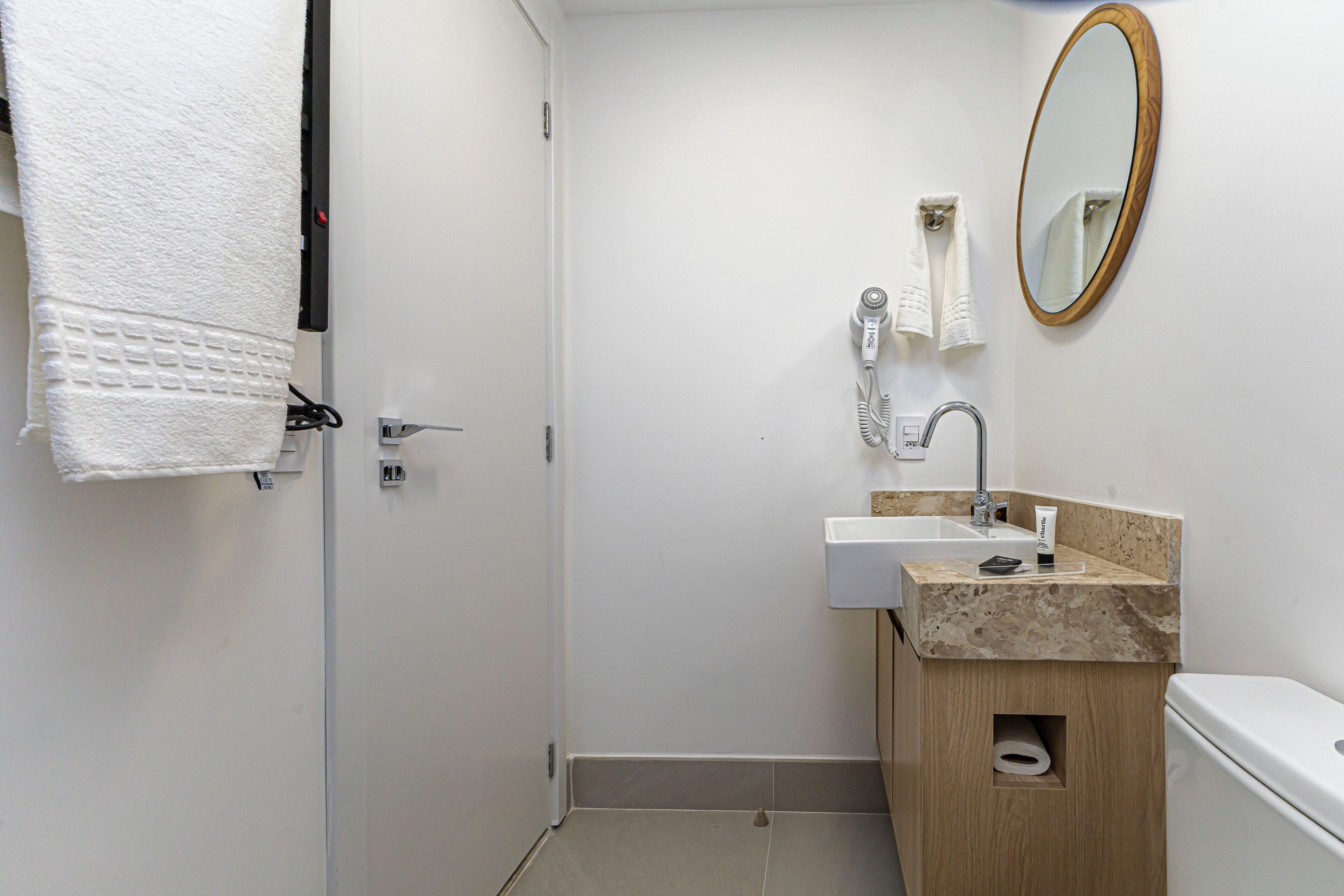 A bathroom with a white sink, a mirror, and a towel hanging on the wall.