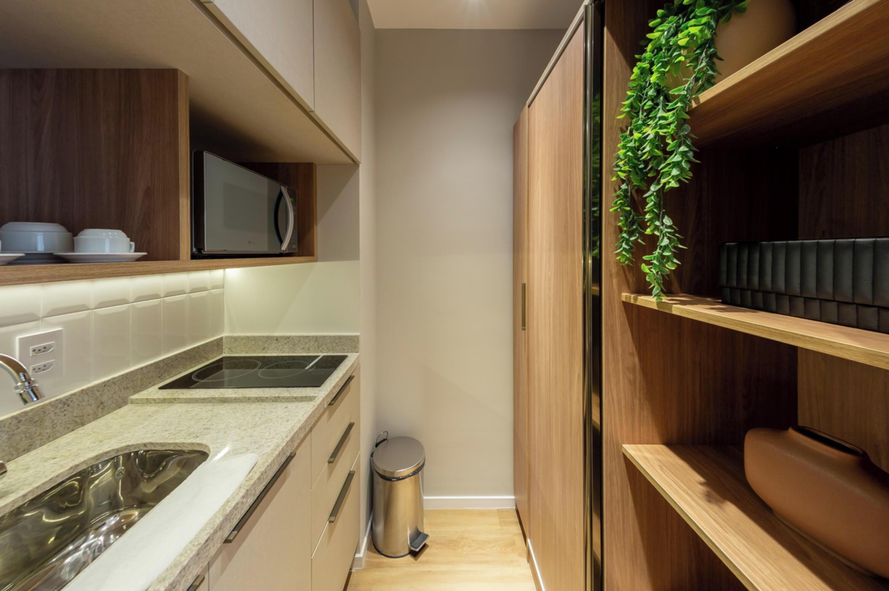 A compact kitchen with a microwave, sink, and trash can.