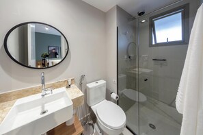 A modern bathroom with a glass-enclosed shower, a white toilet, and a marble sink. - Charlie For You Paraíso (São Paulo)