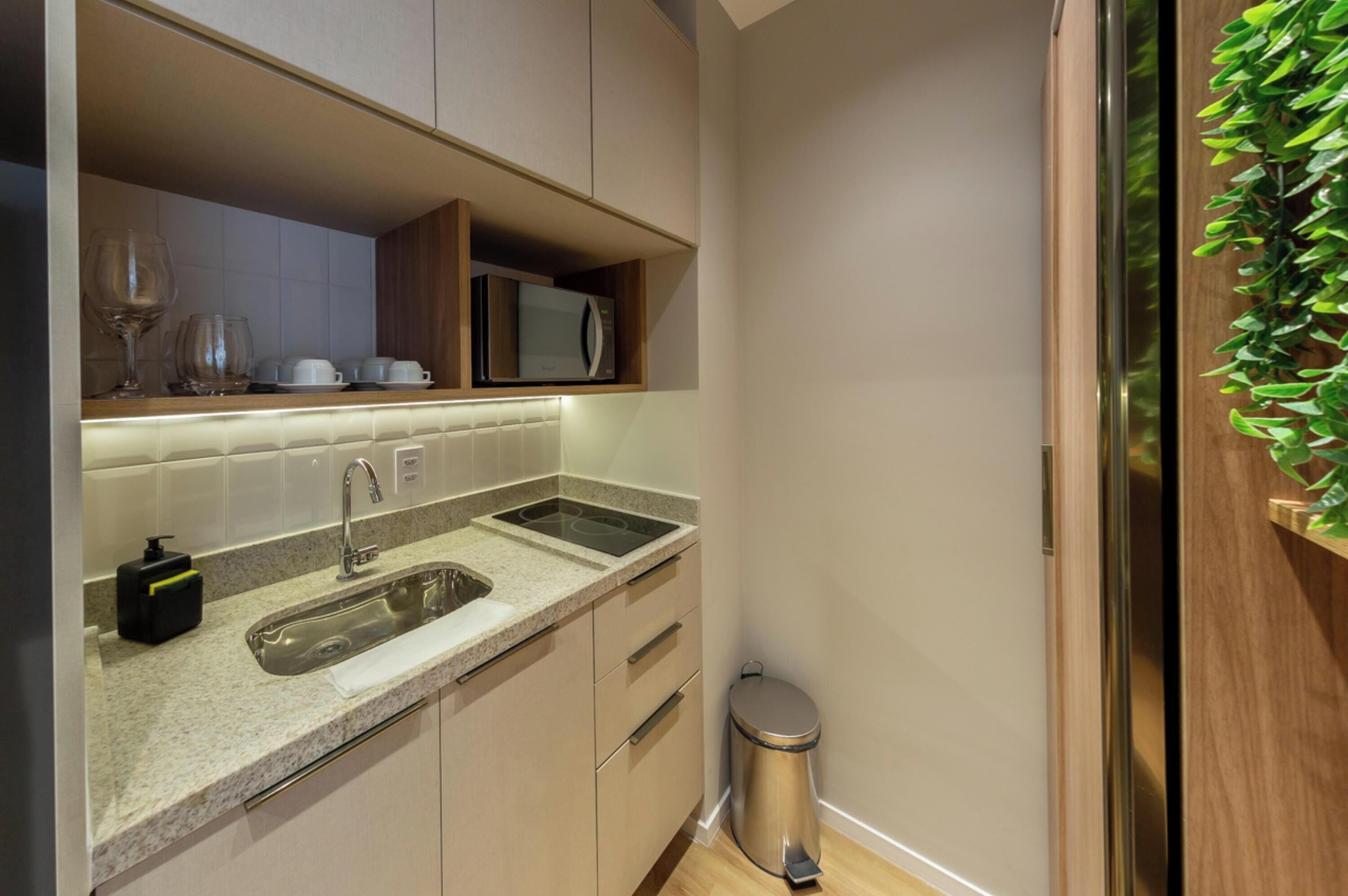 A compact kitchen with a double sink, a microwave, and a small trash bin.