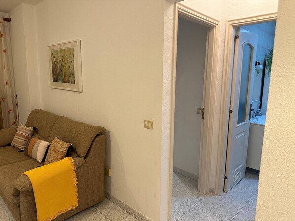 A living room with a brown sofa, a yellow throw blanket, and a framed picture on the wall. - Casa Cabana - El Médano (Granadilla de Abona)