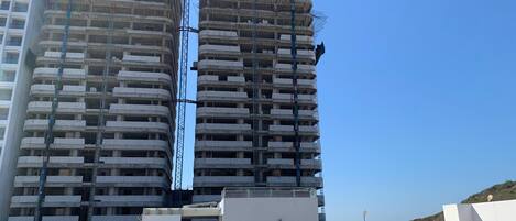 Two high-rise buildings under construction with visible scaffolding and construction workers.