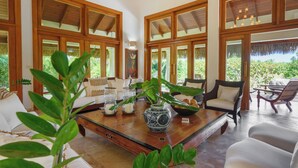 A spacious living area with a wooden coffee table, white sofas, and a large window with a view of greenery. - Escape to Lagunas 2, a serene villa in Cap Cana, perfect for families or groups (Punta Cana)