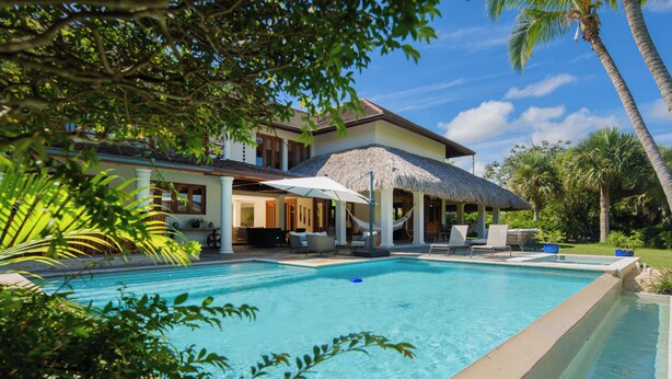 A pool area with a thatched-roof structure, lounge chairs, and palm trees. - Escape to Lagunas 2, a serene villa in Cap Cana, perfect for families or groups (Punta Cana)