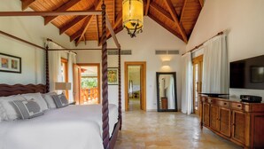 A bedroom with a four-poster bed, wooden ceiling beams, a chandelier, a large mirror, and a television on a wooden cabinet. - Escape to Lagunas 2, a serene villa in Cap Cana, perfect for families or groups (Punta Cana)