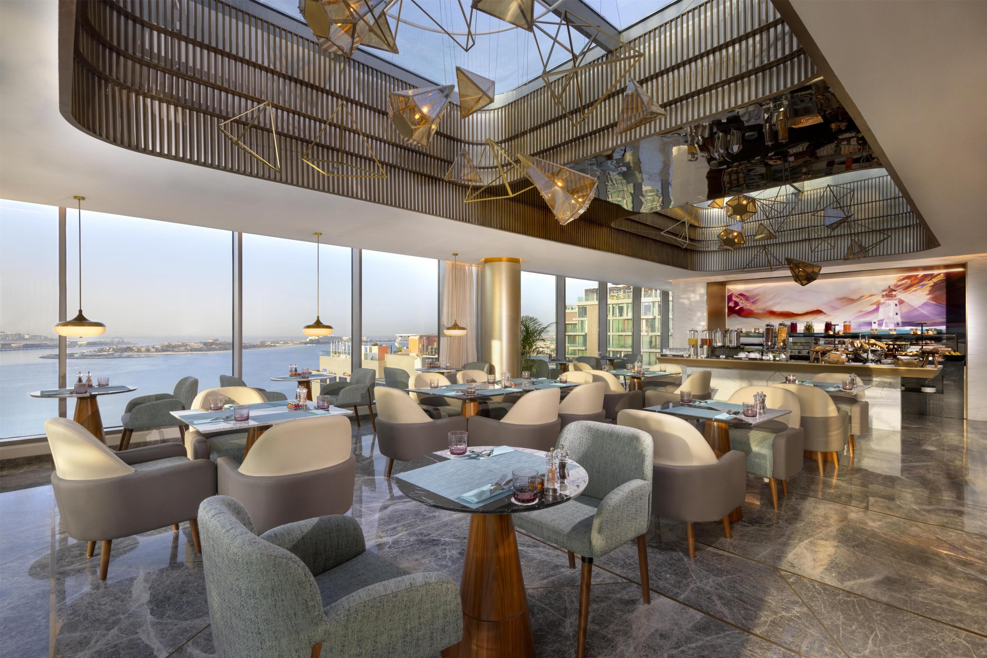 Un espace de restauration moderne, avec des tables et des chaises, un bar et une vue sur l’eau.