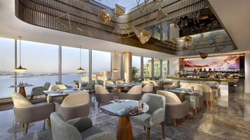 Un espace de restauration moderne, avec des tables et des chaises, un bar et une vue sur l’eau.