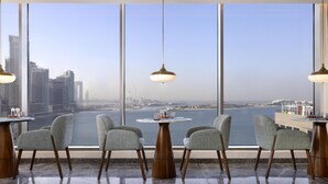 A high-rise room with a large window overlooking a body of water and cityscape. - Tumbi Hotel Dubai The Palm, Tapestry Collection by Hilton (Dubai)