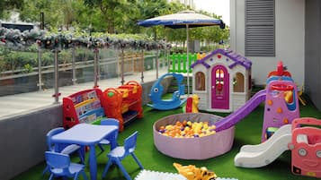 Area giochi all'aperto con scivolo, piscina di palline e strutture di gioco.