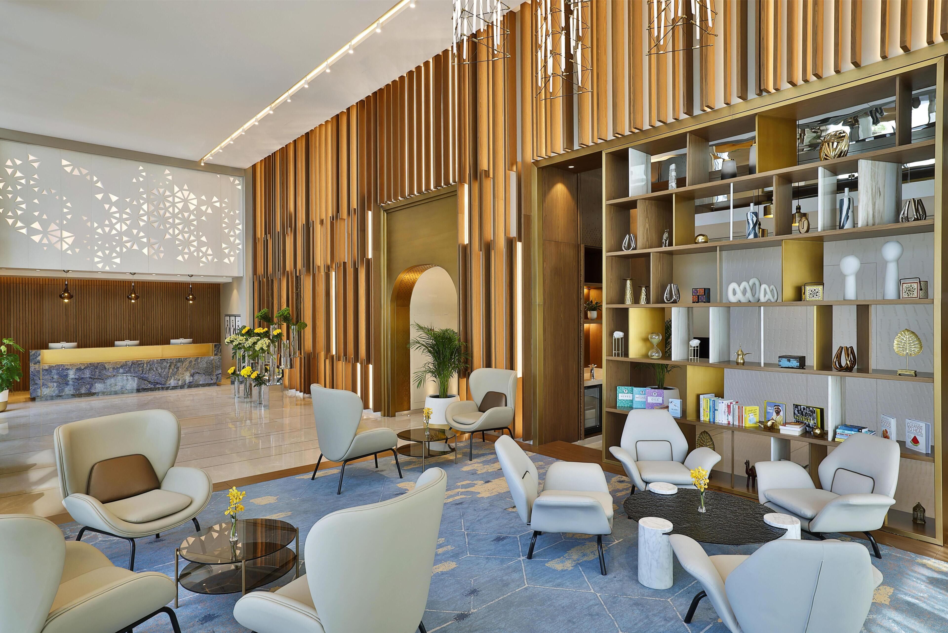 A modern lobby with a reception desk, seating area, and decorative shelves.