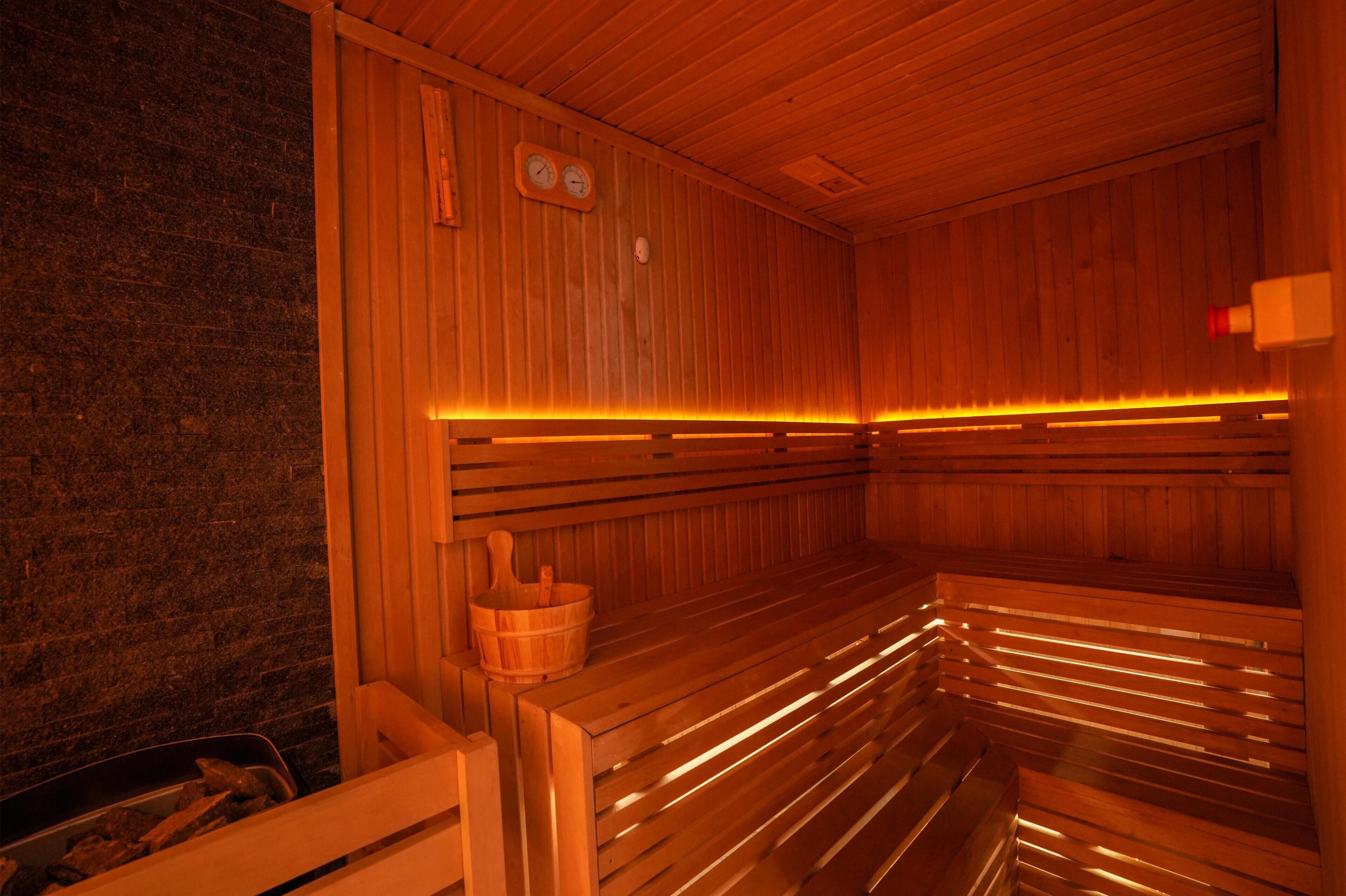 A sauna with wooden benches, a wooden wall, and a brick wall.