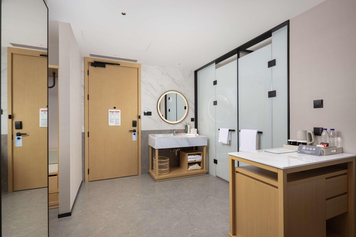 Une salle de bain moderne avec un mur en marbre, un lavabo avec un miroir, un bureau en bois et un porte-serviettes.