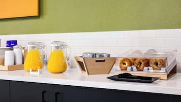 A breakfast bar with orange juice, coffee, and pastries.
