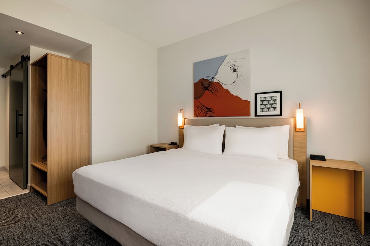 Ein Hotelzimmer mit einem großen Bett, einem Holzschrank und einem Gemälde an der Wand.